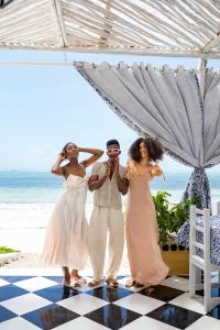 a group of people standing under an umbrella on the beach at ZAN Orient Bwejuu Hotel in Makunduchi