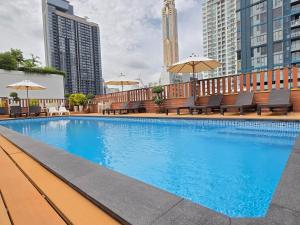 a swimming pool with benches and umbrellas on a building at True Siam Rangnam Hotel in Bangkok