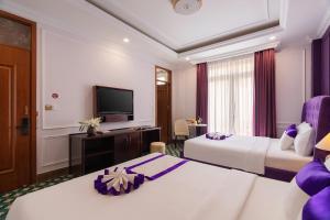 a hotel room with two beds and a flat screen tv at Peach Valley Hotel Dalat in Da Lat