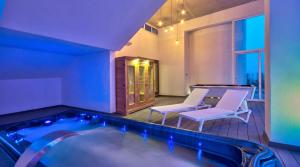 a hot tub in a room with two chairs and avisor at Villa Gaia - Sunset Views, Indoor Heated Pool, Sauna and Games Room in Mellieħa