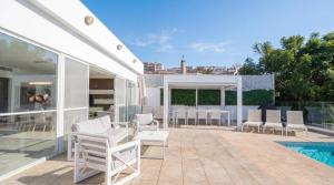a patio with white chairs and a pool at Villa Gaia - Sunset Views, Indoor Heated Pool, Sauna and Games Room in Mellieħa
