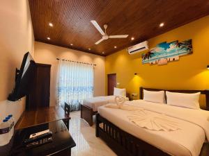 a bedroom with two beds and a flat screen tv at Infenta's Villa Hotel & restaurant in Pandattarippu