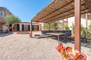 a patio with a wooden table and benches under a pavilion at Casa Can Pauma in Caʼs Concos