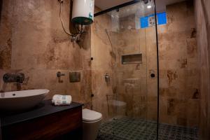 a bathroom with a shower with a sink and a toilet at Enchanted Hills Farmstay in Mukteshwar