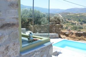 a house with a swimming pool and a window at Villa Rokanes Glass Stone with Pool in Kouvéllai +28 photos