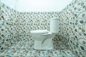 a bathroom with a toilet in a tiled wall at RB Cottage Resort By ARBA in Palayangan