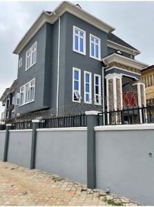 a grey house with a white fence in front of it at Sbk3apartments in Ologode