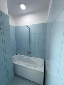 a white bath tub in a white tiled bathroom at Alfas Beach Apartments in Shëngjin +3 photos