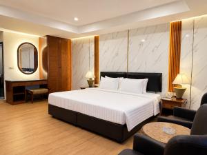 a bedroom with a large white bed and a chair at Nova Park Hotel Pattaya in Pattaya +24 photos