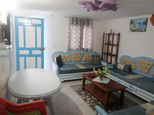 a living room with blue couches and a table at Studio Yakina in El Haouaria