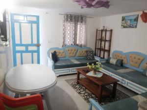 a living room with blue couches and a table at Studio Yakina in El Haouaria
