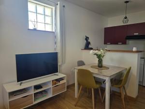 a living room with a table and a television at Appartement le Tilleul - Apparts Cosy in Saint-Pons