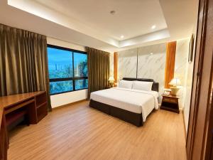 a bedroom with a bed and a desk and a window at Nova Park Hotel Pattaya in Pattaya