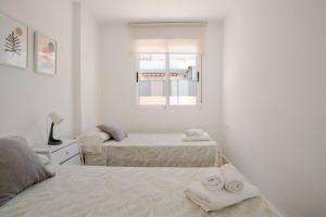 two beds in a white room with towels on them at Ático puerto Burriana in Burriana