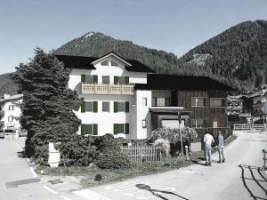 two people standing in front of a large house at Casa Pencio in Pozza di Fassa