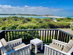 a balcony with chairs and a table and the ocean at i-LOLLO Bed & Breakfast at the River Mouth in St Francis Bay