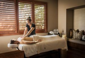 Kobieta robi mężczyźnie masaż na łóżku. w obiekcie Spicers Peak Lodge w mieście Maryvale