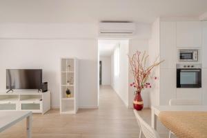 a white living room with a table and a tv at Ático puerto Burriana in Burriana