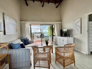 a living room with a couch and a table and chairs at i-LOLLO Bed & Breakfast at the River Mouth in St Francis Bay