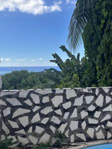 a view of the ocean from behind a stone wall at Lodge Tainas in Faaa
