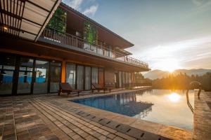 a house with a swimming pool with the sun setting at Villa Favore in Puncak