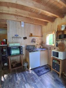 a kitchen with a refrigerator and a sink in a cabin at La cabane de Jane in Saint-Bonnet-lʼEnfantier