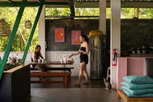 a woman is standing in a kitchen with a table at URALSURF HOUSE in Weligama