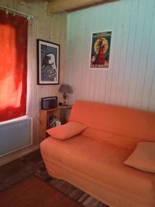 an orange couch in a room with posters on the wall at La cabane de Jane in Saint-Bonnet-lʼEnfantier
