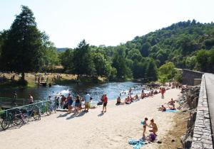 a group of people on a beach next to a river at Votre cocon en Ardèche Verte in Saint-Prix
