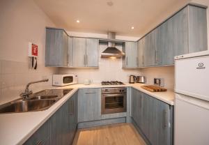 een keuken met blauwe kasten en een wastafel bij White Lodge Apartments in Mawgan Porth +15 foto's