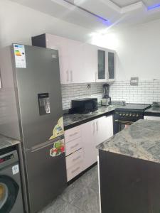 a kitchen with a stainless steel refrigerator and white cabinets at Sbk3apartments in Ologode