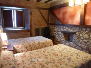 a bedroom with two beds and a stone fireplace at Posada El Pozo in Castanedo