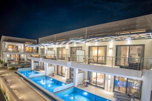 an apartment building with a swimming pool at night at Evaeri Suites in Mytikas