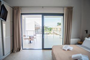 a bedroom with a bed and a balcony with a table at Evaeri Suites in Mytikas +55 photos