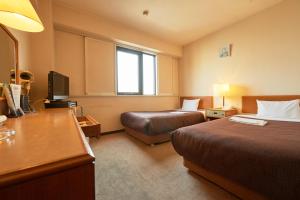 a hotel room with two beds and a desk at Hotel Select Inn Hachinohe Chuo in Hachinohe