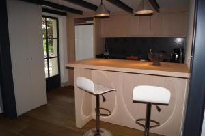 una cucina con bar con due sgabelli bianchi di Domaine de la Girafe a Eyragues Altre 10 foto