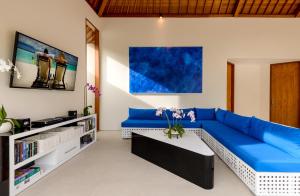 ein Wohnzimmer mit einem blauen Sofa und einem Tisch in der Unterkunft Villa Ley Seminyak by Best Deals Asia Hospitality in Seminyak