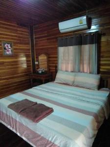 a large bed in a wooden room with avertisement at Baanraimaetha Resort in Bān Phea