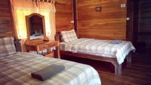 two beds in a room with wooden walls at Baanraimaetha Resort in Bān Phea