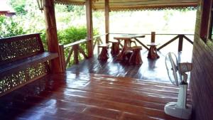a porch with a wooden floor and a table and benches at Baanraimaetha Resort in Bān Phea
