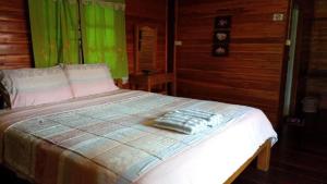 a bed in a room with a green curtain at Baanraimaetha Resort in Bān Phea