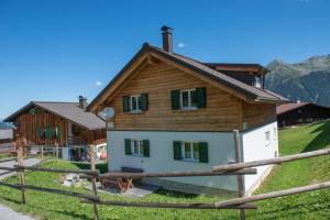 ein Haus auf einem Hügel mit einem Zaun davor in der Unterkunft Ferienhäuser Tschofen Garfrescha in Sankt Gallenkirch