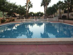 una gran piscina con una valla blanca y palmeras en Gran Alacant Apartment, en Puerto Marino