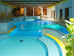 uma grande piscina com azulejos azuis no chão e tectos em Reit-und Sporthotel Nordmann em Stangerode