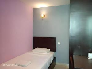 a bedroom with a white bed with a light on the wall at BB Motel in Alor Setar