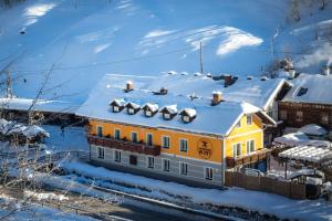 a yellow building with snow on the roof at Gasthof zum Hammer in Göstling an der Ybbs