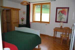 a bedroom with a bed and a desk and a window at Chambre d'hôtes Kieffer Le Grand Bienfaisy in Remiremont