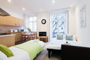 a room with two beds and a kitchen with a clock at Dream South Kensington Apartment in London