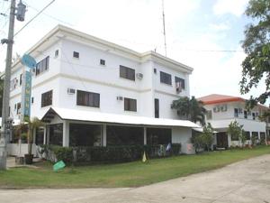 a large white building with windows and a street at Jamont Hotel in Sipalay