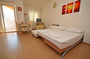 a bedroom with a bed and a table and a window at Apartments Jela in Metajna